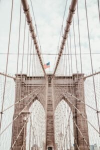 Stunning view of the Brooklyn Bridge with an American flag, symbolizing New York City's architectural grandeur.