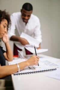 Two adults working together at a desk in a modern office setting, engaged in planning.